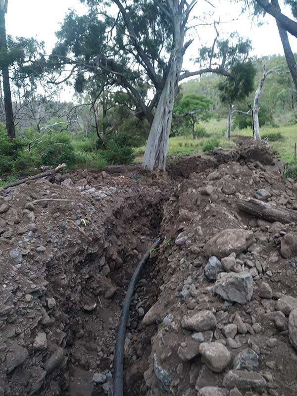 Deep trench through creek crossing with waterpipe dropped in