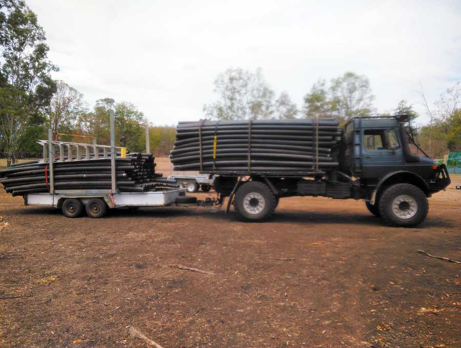 Unimog carrying large poly water pipe to farm